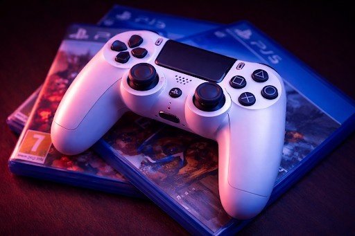 Sony PS5 DualSense controller on PlayStation 5 game cases with blue and red lighting