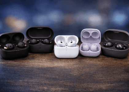 Close-up of multiple wireless earbuds in open charging cases placed side by side on a table with a blurred background, showcasing modern design and premium build quality.